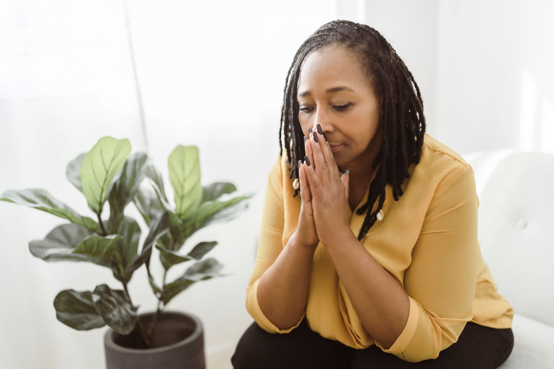 Portrait of an african woman sit on the sofa and pray